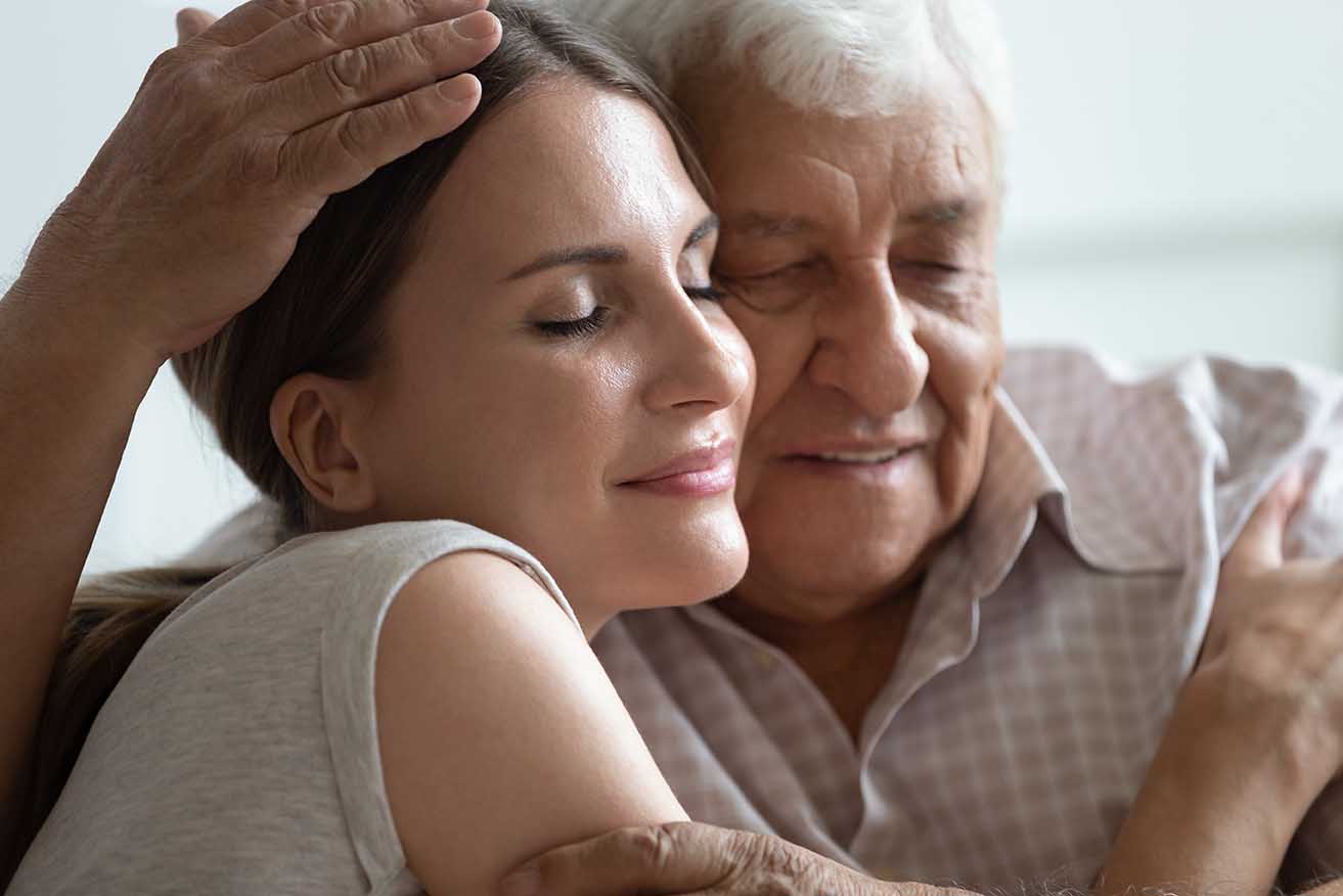 Older hoary man hugging loving grown up daughter at home.